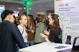 Besucherinnen und Besucher im Gespräch mit einer HSD-Vertreterin an einem Informationsstand zur Kindheitspädagogik bei der Nacht der Wissenschaft in Düsseldorf.
